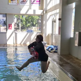 a lifeguard jumping in the pool.