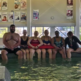 6 lifeguards smiling and chatting poolside.