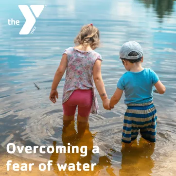 two children stepping into shallow water. 