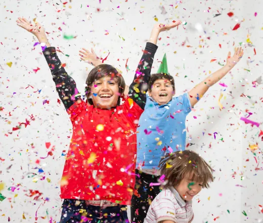 Children throwing their arms in the air in celebration while confetti fills the air.