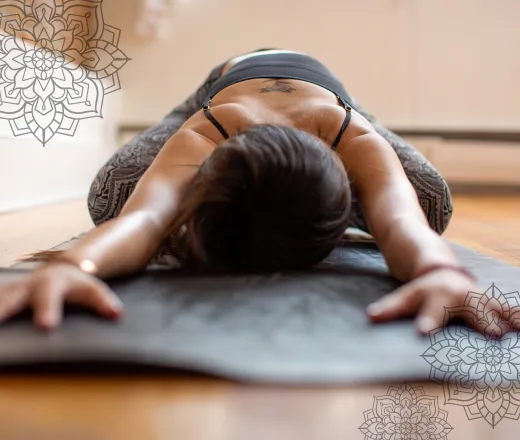 a photo of a woman lying on a yoga mat in child's pose. There are intricate mandalas framing the image.