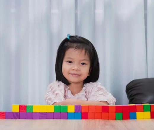 A little girl with colorful building blocks in front of her.