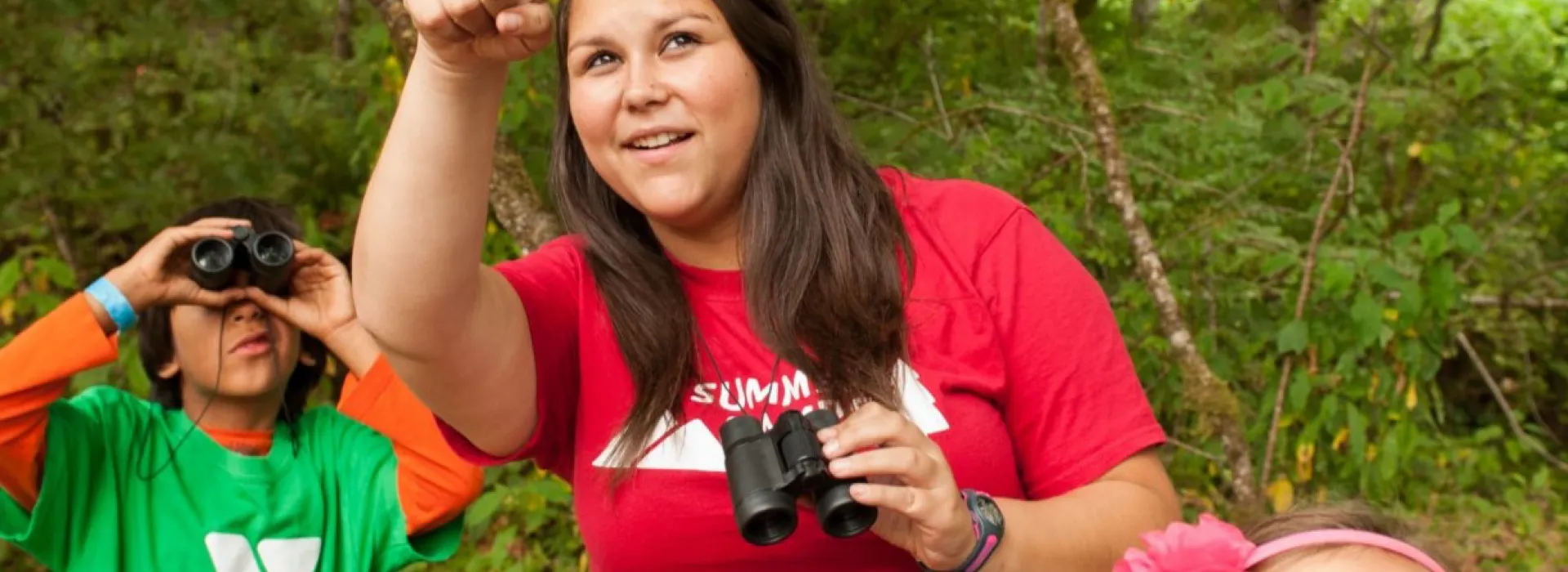 A camp leader showing kids how to use their binoculars.
